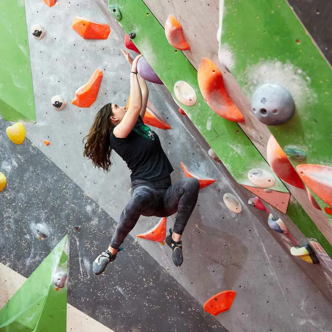 A climber reaching for a hold on an indoor wall