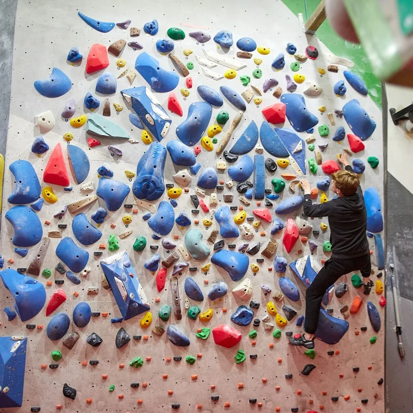 A wide bouldering wall covered in colourful holds