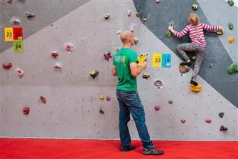 Young climbers on a colourful slab wall above thick matting
